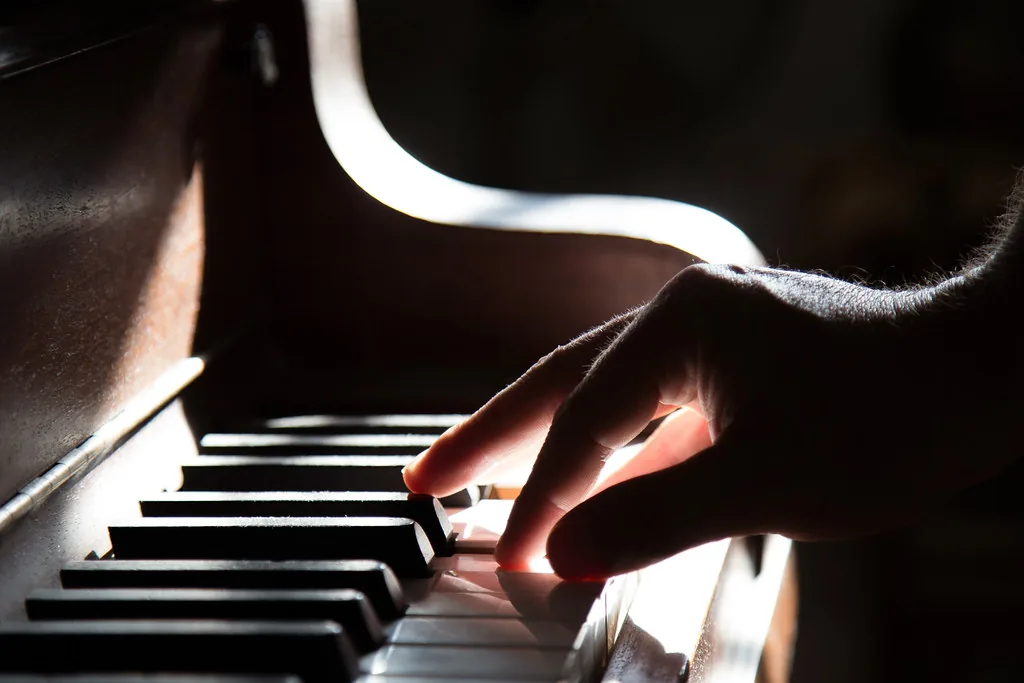 Hand playing an acoustic piano